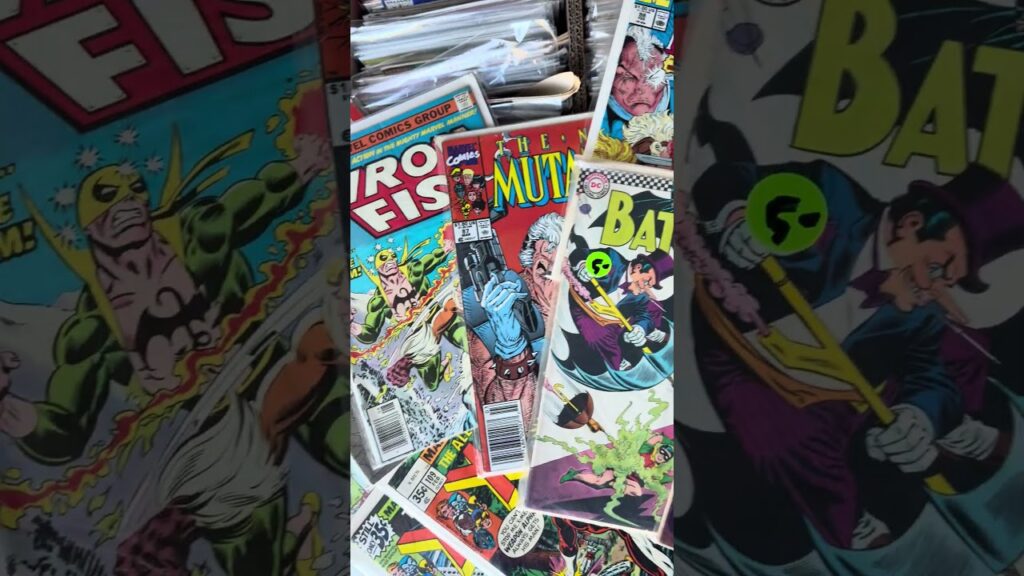 Iron Fist, New Mutants and Batman comic books fanned out over a short box of bagged comics